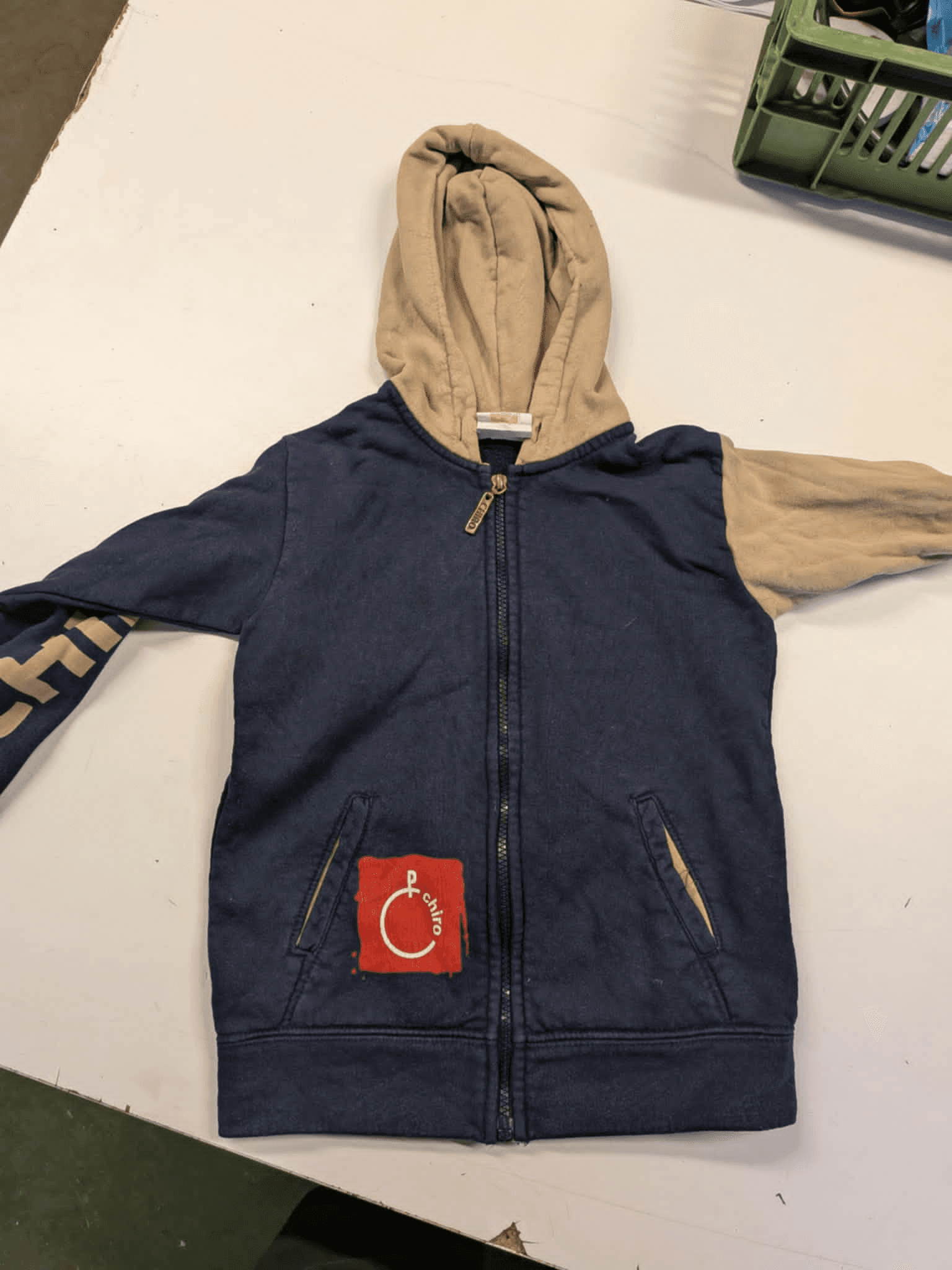 a blue and tan hoodie with a red patch on the pocket that says charity